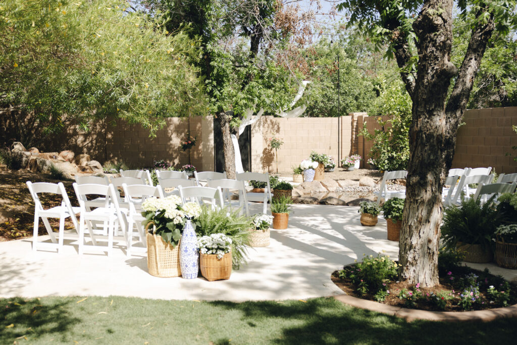 Backyard wedding ceremony setup with white chairs and garden-inspired florals.