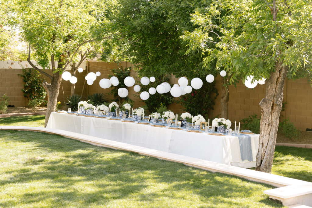 Elegant backyard wedding reception table with white lanterns and blue details.